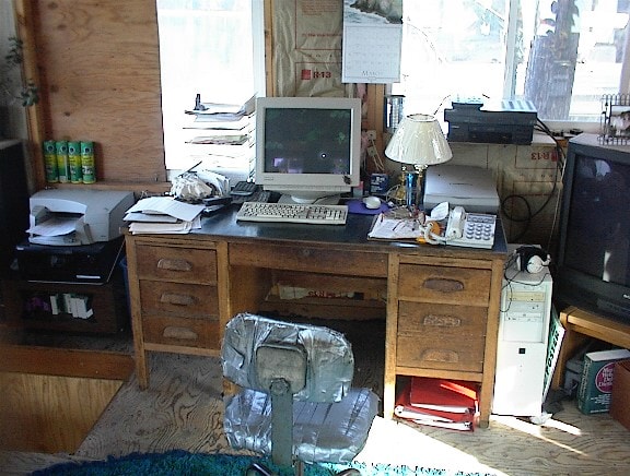 Cluttered wooden desk with old computer and office equipment inside the houseboat